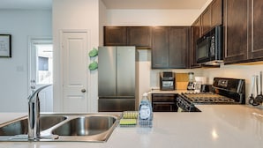 Una cocina moderna con electrodomésticos de acero inoxidable, un lavamanos doble y armarios de madera.
