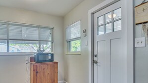Ein Zimmer mit einem Holzkasten, einer Tür und einem Fenster mit Jalousien.