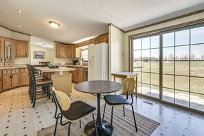 Una cocina con armarios de madera, una mesa de comedor con sillas y un amplio ventanal corredera que ofrece vistas.