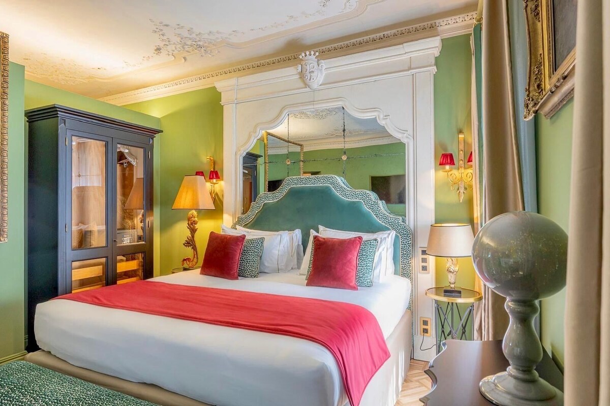 Una habitación de hotel con una cama, un armario, un espejo y una lámpara.