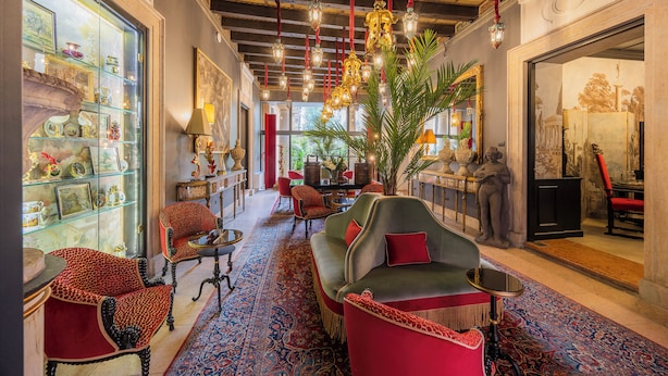 A spacious lobby with a red sofa, chairs, a large plant, and a glass display case. - PALAZZO TREZZA VERONA Preferred Hotels & Resorts (Verona)