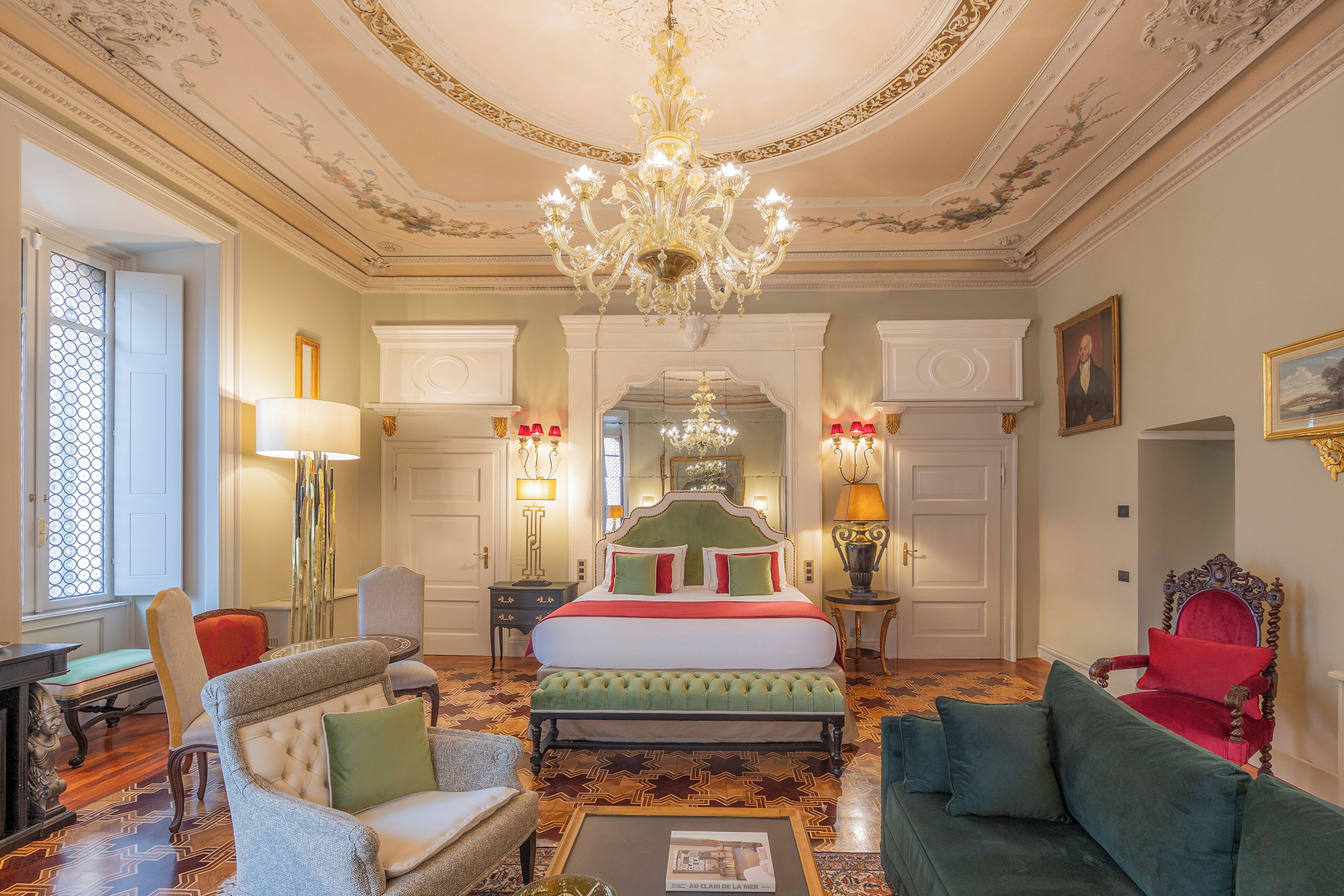 A luxurious bedroom with a large bed, ornate ceiling, and classic furniture.