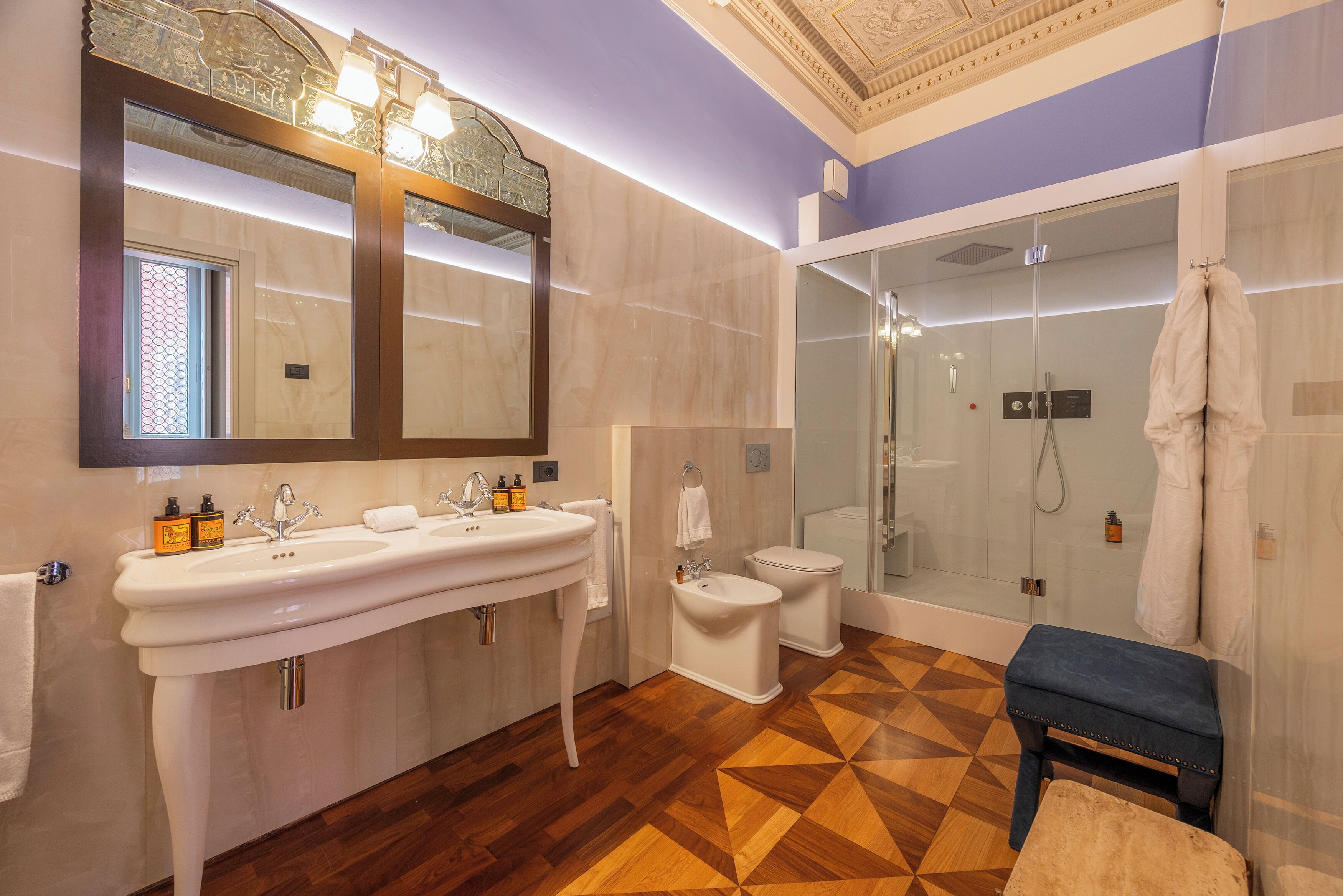 A bathroom with a double sink, toilet, and walk-in shower.