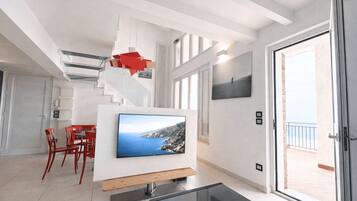 Ein modernes Wohnzimmer mit Fernseher, roten Sesseln, einer Treppe und einem Balkon.