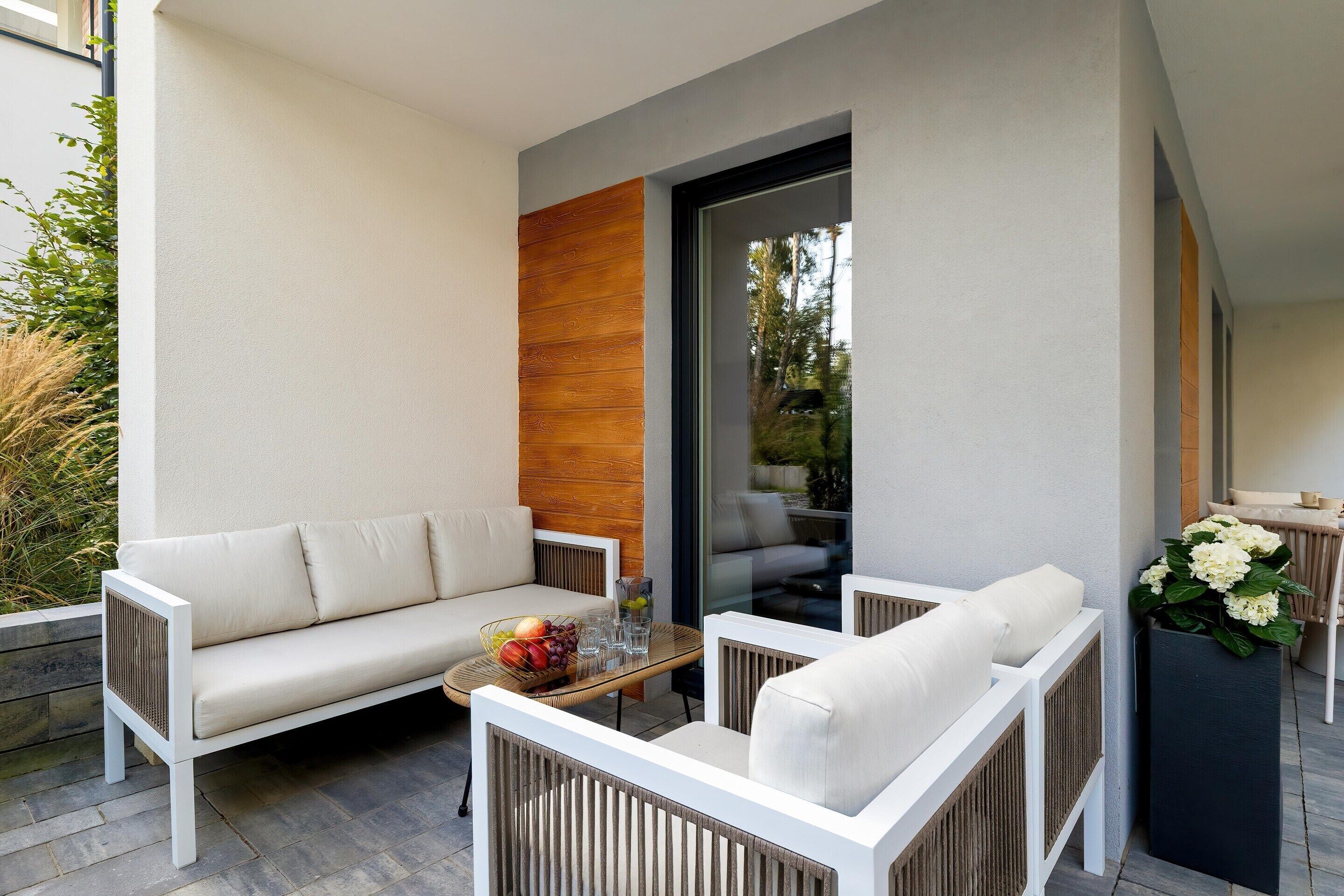 A modern outdoor seating area with a sofa, chairs, and a table.