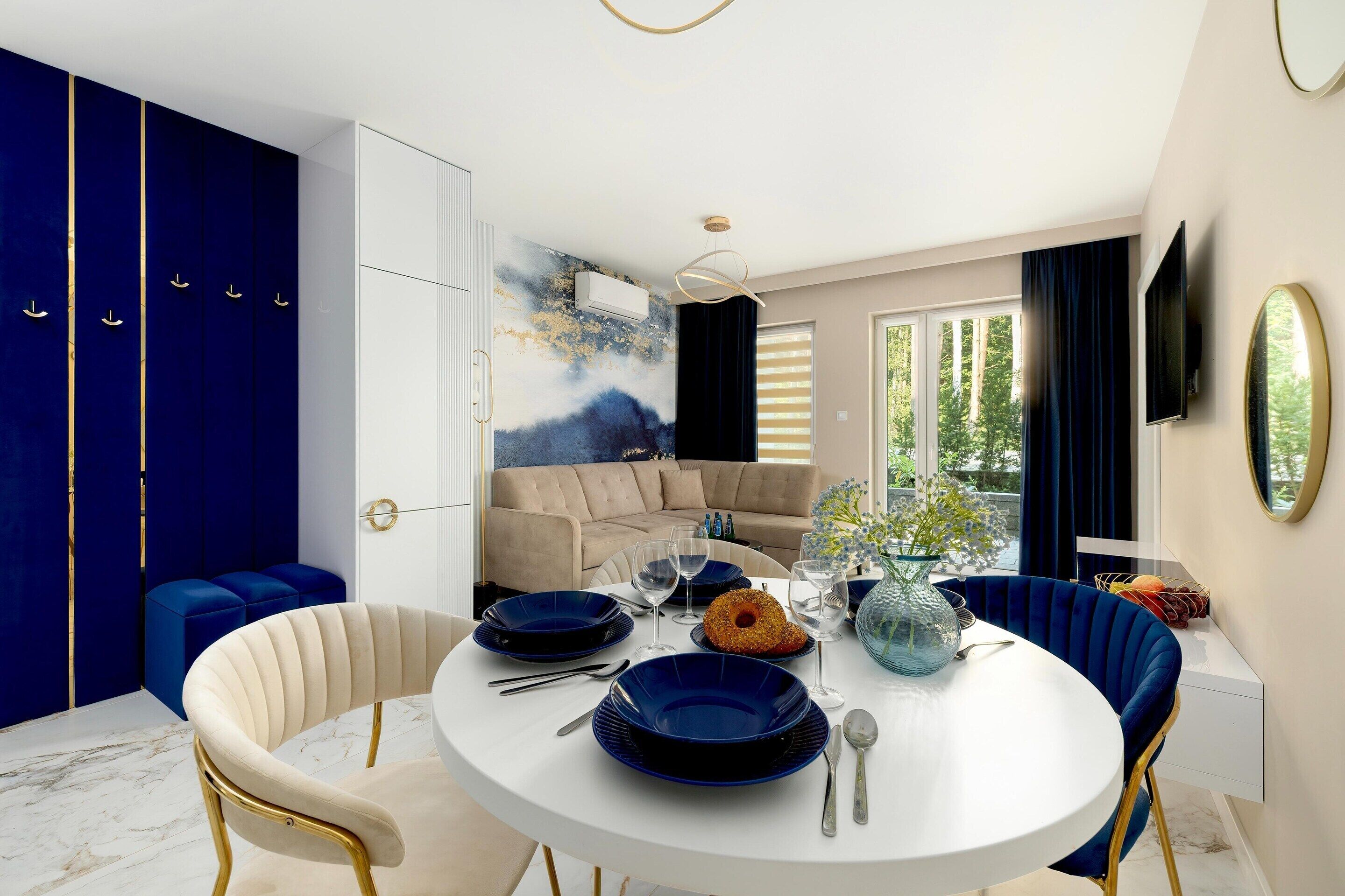 A dining area with a round table, blue plates, and a vase of flowers.