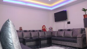 Un salon moderne avec un canapé d’angle, un téléviseur à écran plat et des coussins décoratifs.