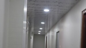 Un couloir étroit doté d’un revêtement de sol à motifs, d’un éclairage encastré et de portes d’un seul côté.