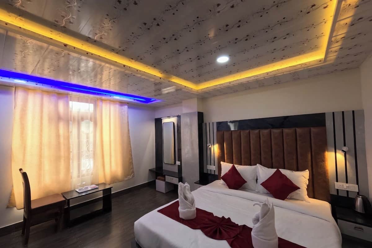 Una habitación de hotel con una cama grande, mesitas de noche, un espejo y suelo de madera.