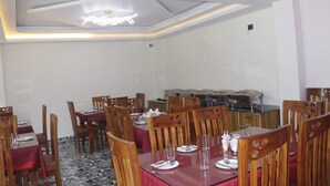 Un espace repas avec des tables rondes, des chaises en bois et un buffet.