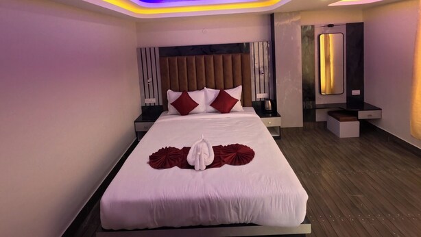 Une chambre d’hôtel moderne avec un grand lit, des tables de chevet, un miroir et un plancher en bois.