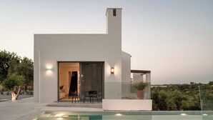 Ein modernes Haus mit Pool, Terrasse und Blick auf die Landschaft.