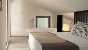 Ein modernes Schlafzimmer mit einem großen Bett, einer Badewanne und einem Fenster.