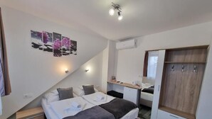A hotel room with a bed, bedside table, desk, wardrobe, and a wall-mounted air conditioner. - Heléna Hotel & SPA (Levél)