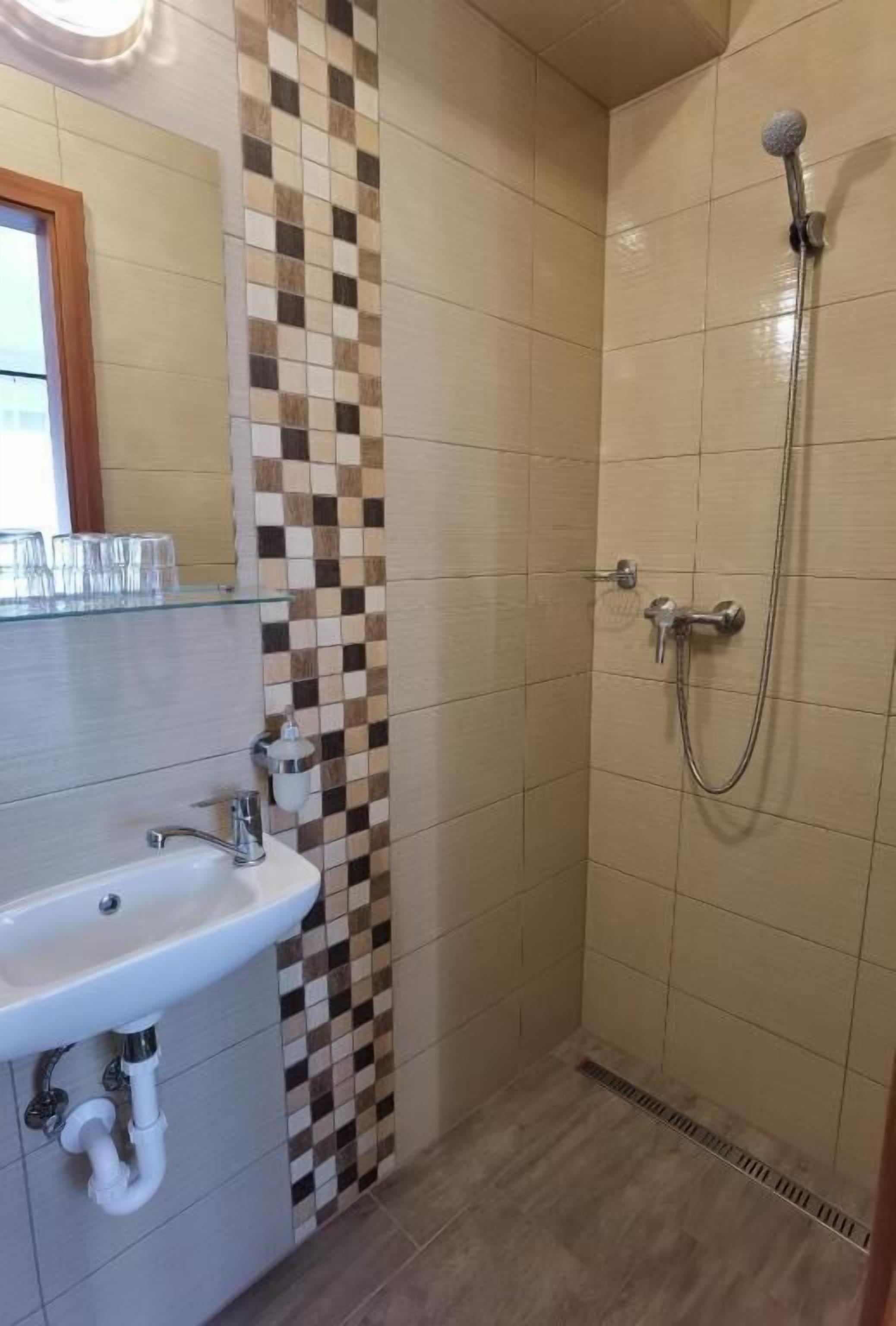 Un baño con lavamanos, espejo y ducha.
