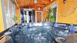 A hot tub area with wooden ceiling, potted plants, and a view of the room. - Heléna Hotel & SPA (Levél)