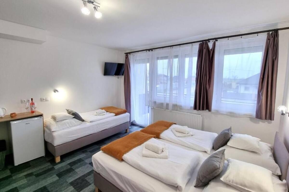 Habitación de hotel con dos camas, un escritorio, un televisor y una ventana con cortinas.