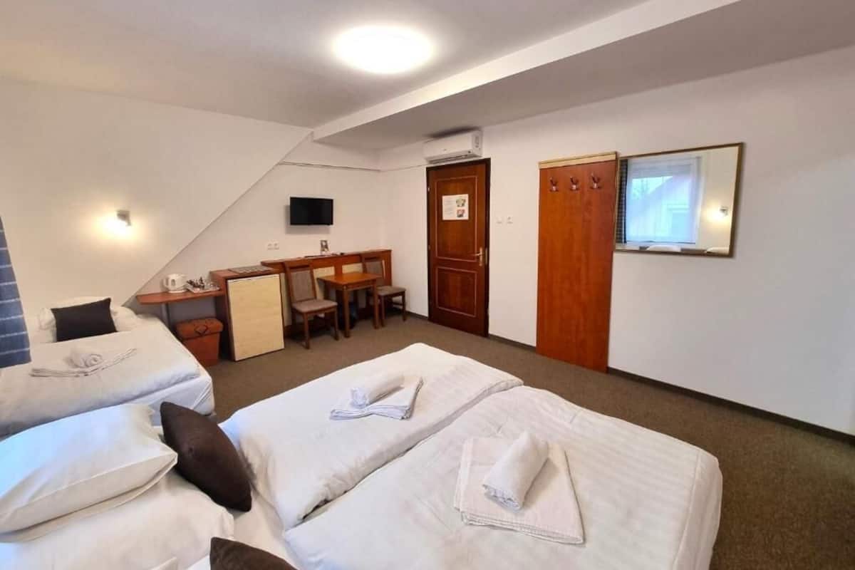 Habitación de hotel con dos camas, un escritorio, una silla, un televisor y una puerta.