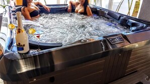 A hot tub with two people, a bottle of champagne, and a glass. - Heléna Hotel & SPA (Levél)