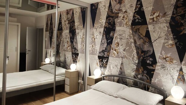 A bedroom with two beds, a mirrored ceiling, and a geometric patterned wall. - House of Mirrors Belgrade (Beograd)