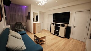 A living room with a sofa, a coffee table, a TV, and a cabinet. - House of Mirrors Belgrade (Beograd)