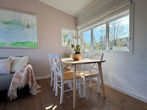 A dining area with a wooden table and chairs, a potted plant, and a painting on the wall. - Seaside Summer House with Stunning Oslofjord Views - Private & Peaceful (Akershus)