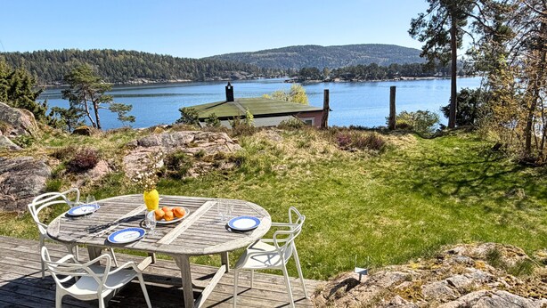 Terraza de madera con una mesa y sillas, con vista a un lago.