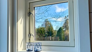 Una ventana con vistas a árboles y un cielo despejado.