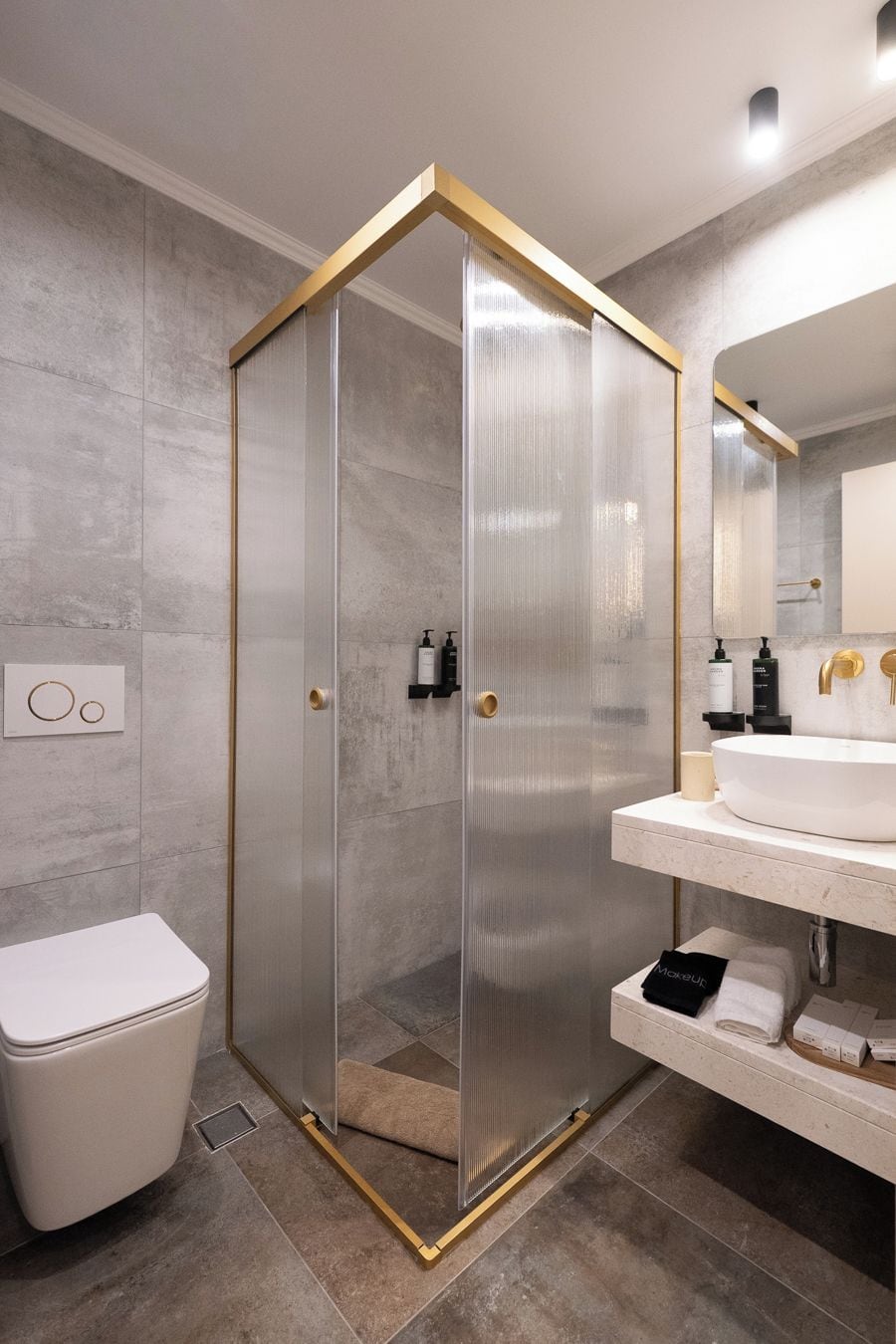 A modern bathroom with a glass-enclosed shower, a white toilet, and a vanity with a sink and mirror.