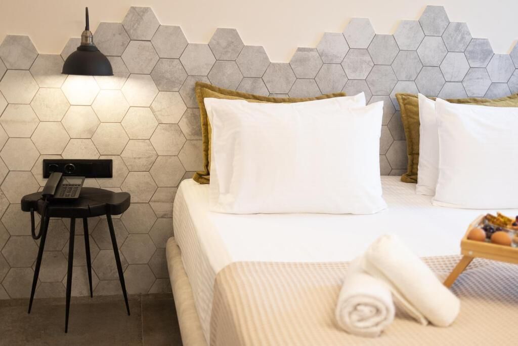 A hotel room with a bed, a desk with a telephone, a lamp, and a tray of eggs.