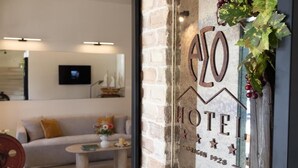 A hotel sign with 'Hotel' and 'Founded 1928' visible, a brick wall, a sofa, a coffee table, and a television on the wall. - ASO Hotel - Historic Raisin Warehouse 1928 (Kalamata)