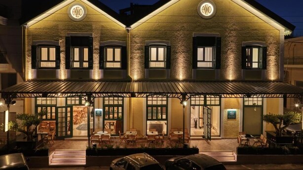A two-story building with a restaurant on the ground floor, featuring outdoor seating and a covered entrance. - ASO Hotel - Historic Raisin Warehouse 1928 (Kalamata)
