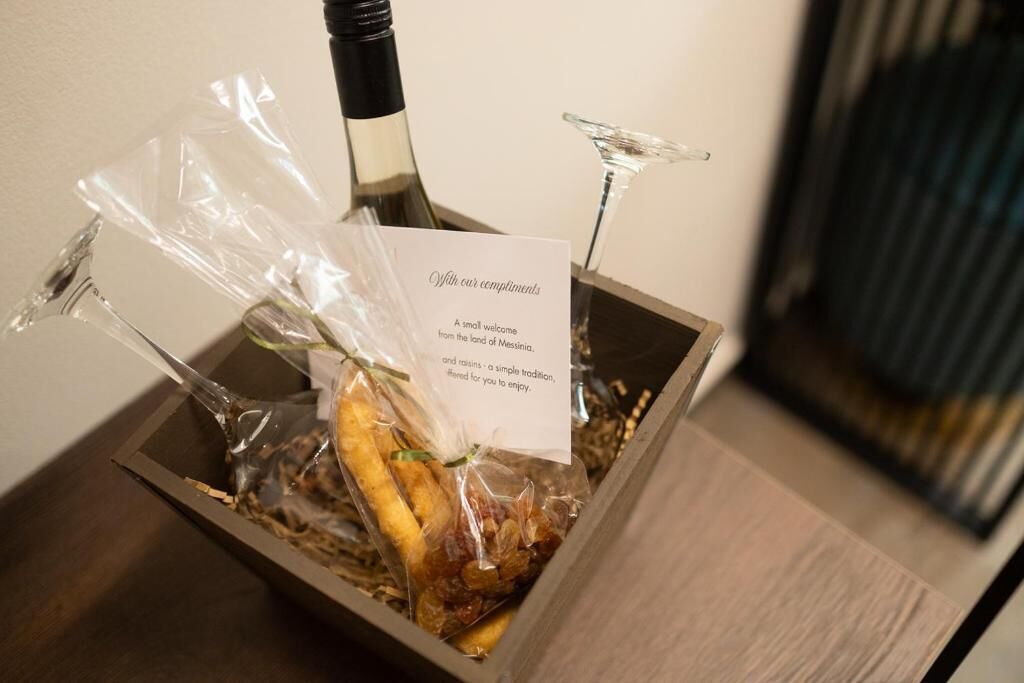 A box with a bottle and a glass, containing dried fruits and nuts, with a card that reads 'Yours our compliments.'