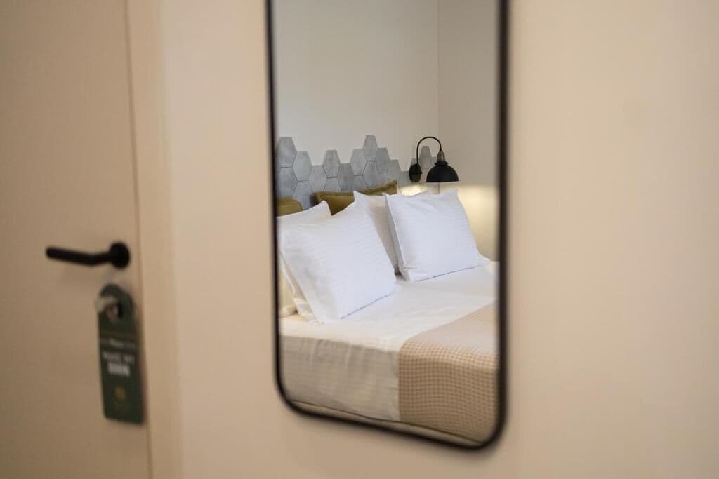 A hotel room with a bed, a headboard with a geometric pattern, a bedside lamp, and a door with a keycard lock.