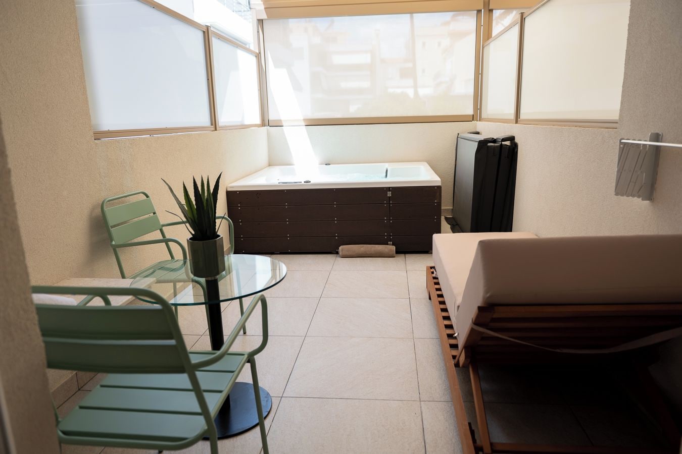 A compact room with a glass table, two chairs, a sofa, a storage unit, and a television.