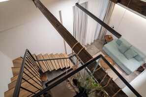 Un interior moderno con una escalera de madera, un sofá azul claro y una pequeña mesa redonda con un jarrón.