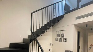 A modern interior with a black staircase, a white sofa, and a covered chair. - ASO Hotel - Historic Raisin Warehouse 1928 (Kalamata)