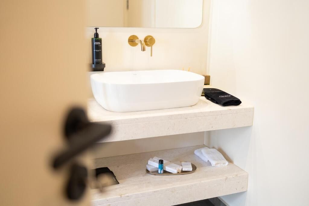A bathroom with a white sink, a mirror, and a towel rack.
