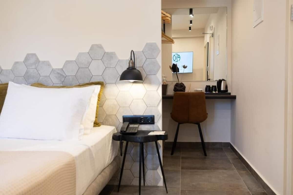 Une chambre d’hôtel avec un lit, un bureau doté d’une lampe, une chaise et un miroir.