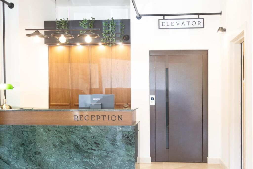 Una recepción con un ordenador portátil Lenovo, armarios de madera y un cartel que indica un ascensor.