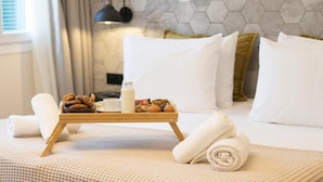 A neatly made bed with a tray of breakfast items, a lamp, and a hexagonal wall design. - ASO Hotel - Historic Raisin Warehouse 1928 (Kalamata)
