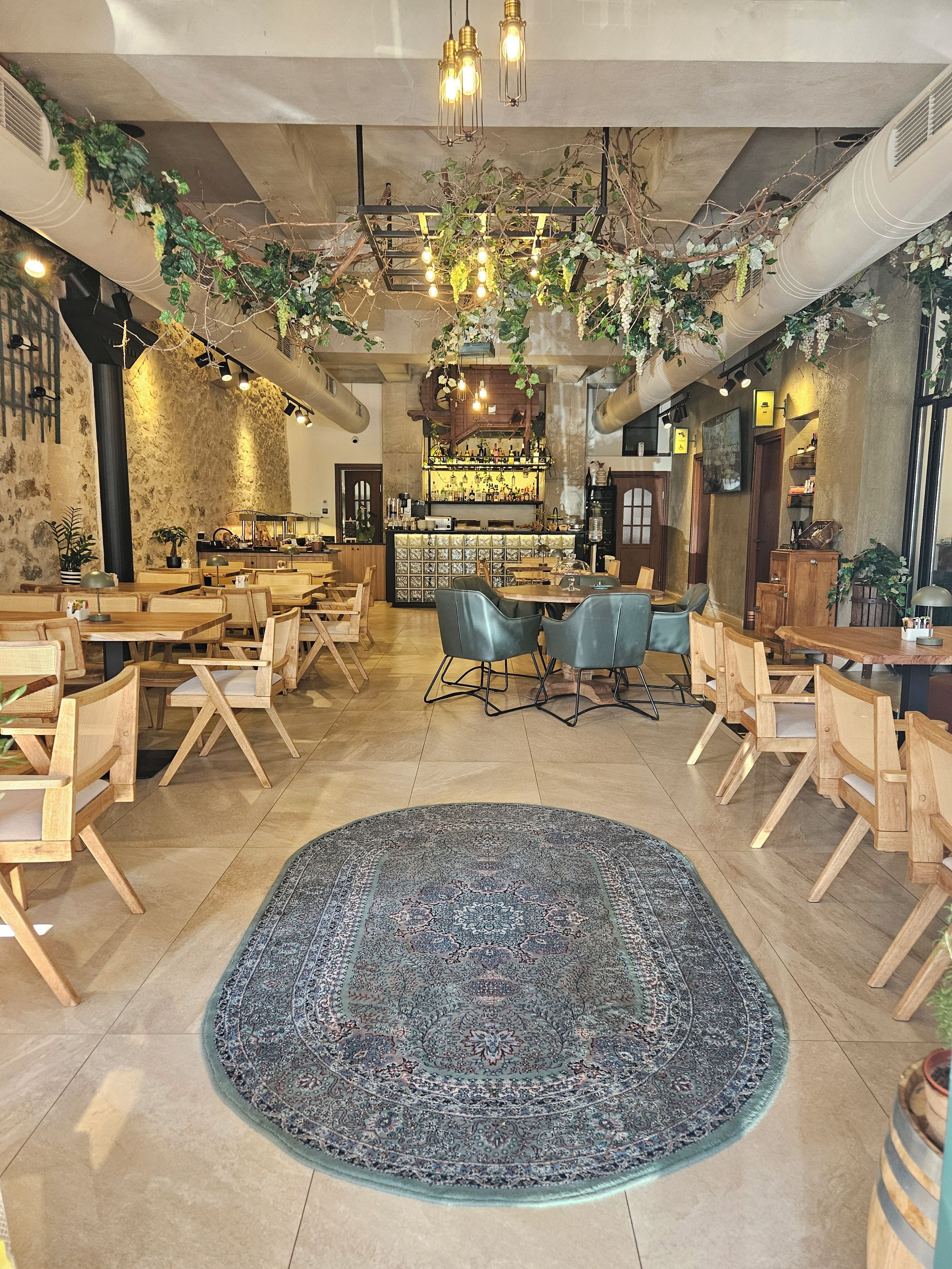 A spacious restaurant with a central bar area, multiple seating arrangements, and decorative plants.