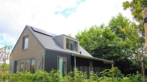 A modern house with a sloped roof, large windows, and a well-maintained garden. - Modern Coastal Retreat With Garden (Sint Maarten)