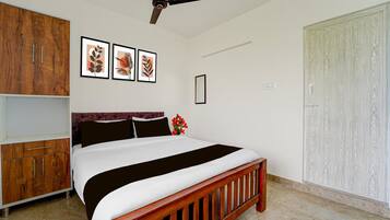 Ein Schlafzimmer mit Bett, Holzschrank, Deckenventilator, gerahmtem Kunstwerk und einer Schranktür.