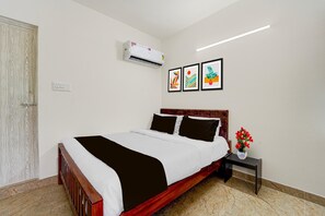 A hotel room with a bed, a nightstand, a vase with flowers, and three framed artworks on the wall.
