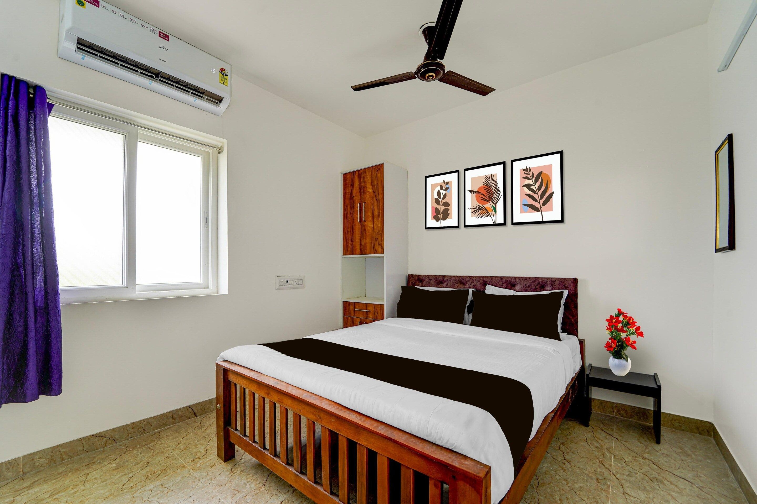 A bedroom with a bed, a ceiling fan, a window with curtains, a wall-mounted air conditioner, and framed artwork.
