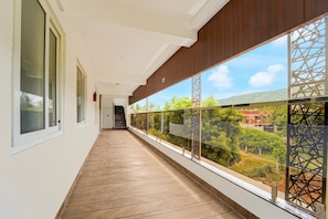 A corridor with a view of a lush landscape, a staircase, and a fire extinguisher.