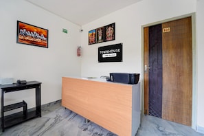Un mostrador de recepción con detalles de madera, un extintor en la pared y una puerta con la etiqueta '101'.