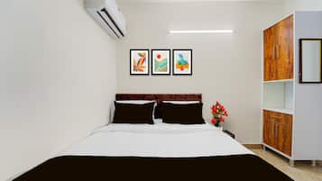 A hotel room with a bed, a wardrobe, and three framed artworks on the wall.