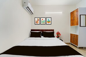 Una habitación de hotel con una cama, un armario y tres cuadros en la pared.